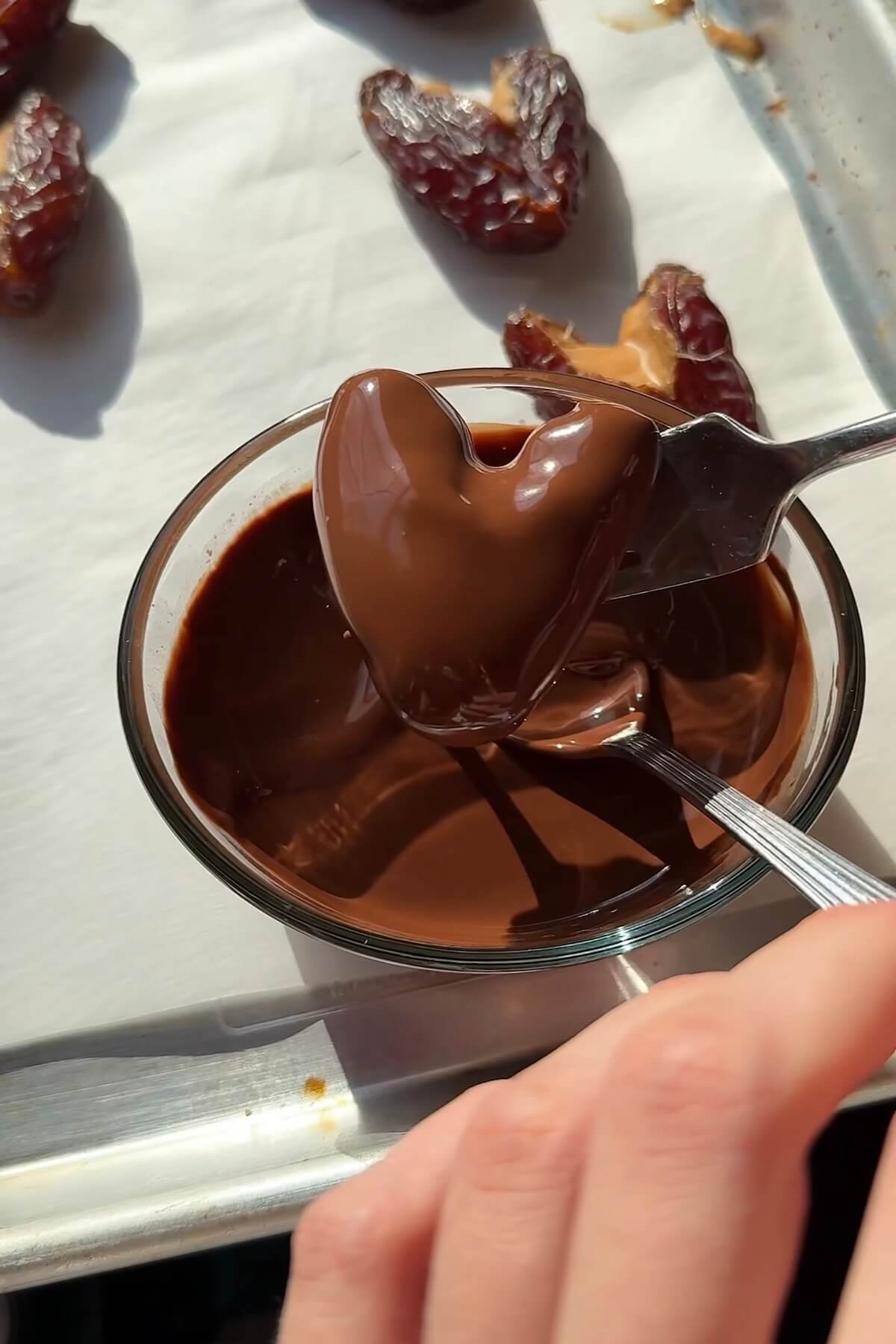 Dipping heart-shaped medjool dates into melted vegan chocolate.