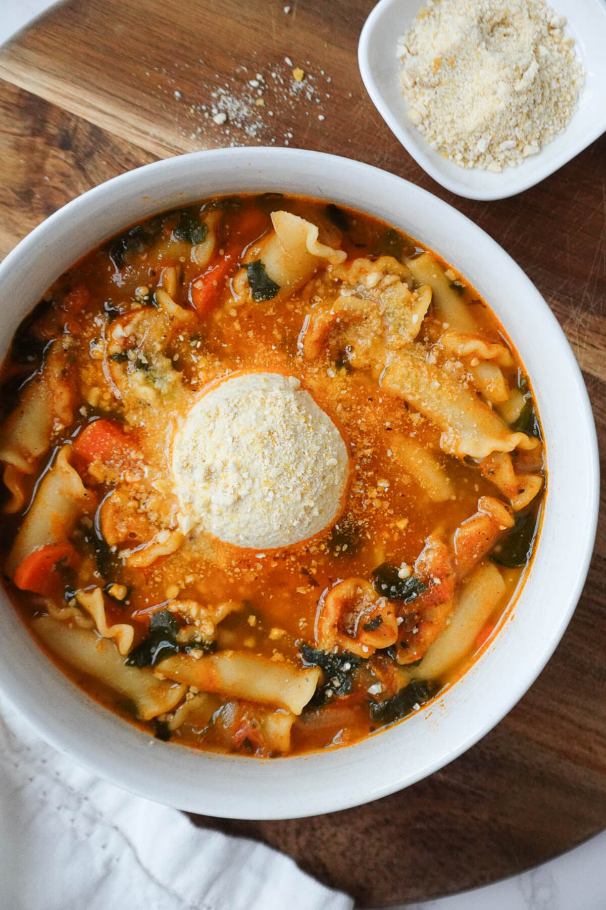 Bowl of vegan lasagna soup with hearty veggies, red lentils, noodles, tofu ricotta, and cashew parmesan.