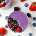 Peanut butter and jelly smoothie in a glass, topped with fresh berries