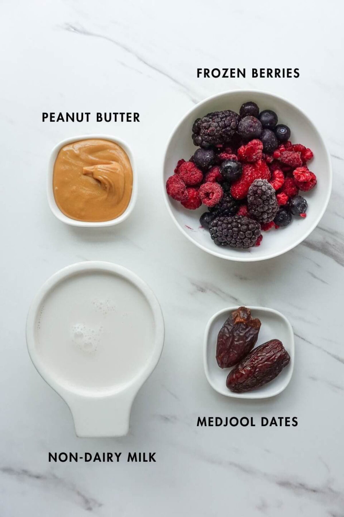 Ingredients for peanut butter and jelly smoothie including frozen berries, peanut butter, medjool dates, and non-dairy milk