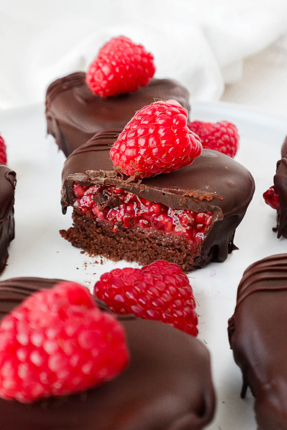 Close-up of a no-bake chocolate-coated brownie with a layer of 3-ingredient raspberry chia jam inside, showing it's rich and fudgy texture.