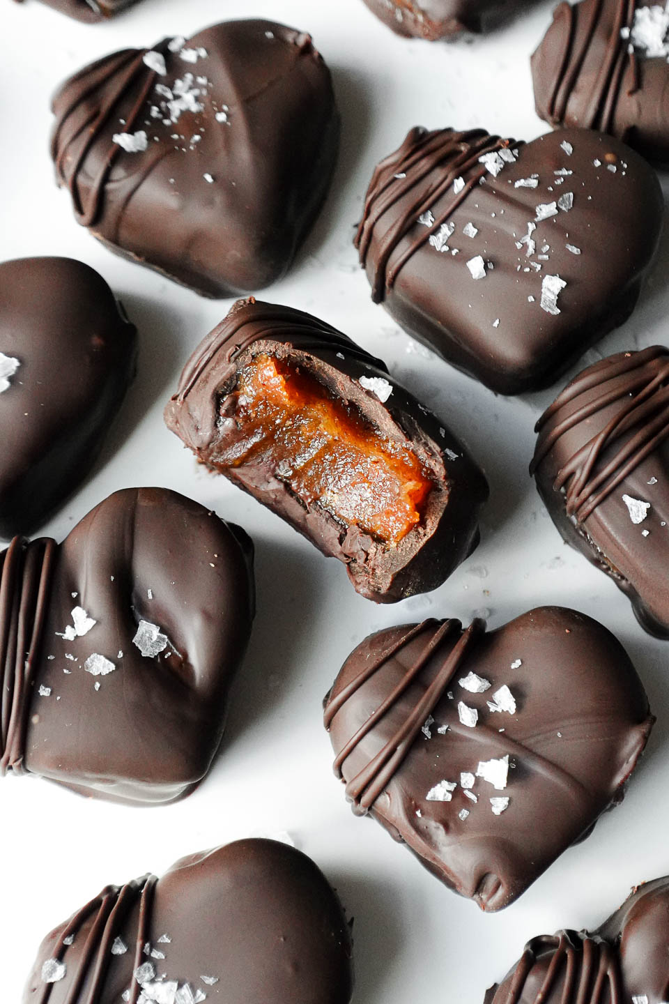 Close-up of a chocolate date caramel with a bite taken out showing it's gooey texture inside