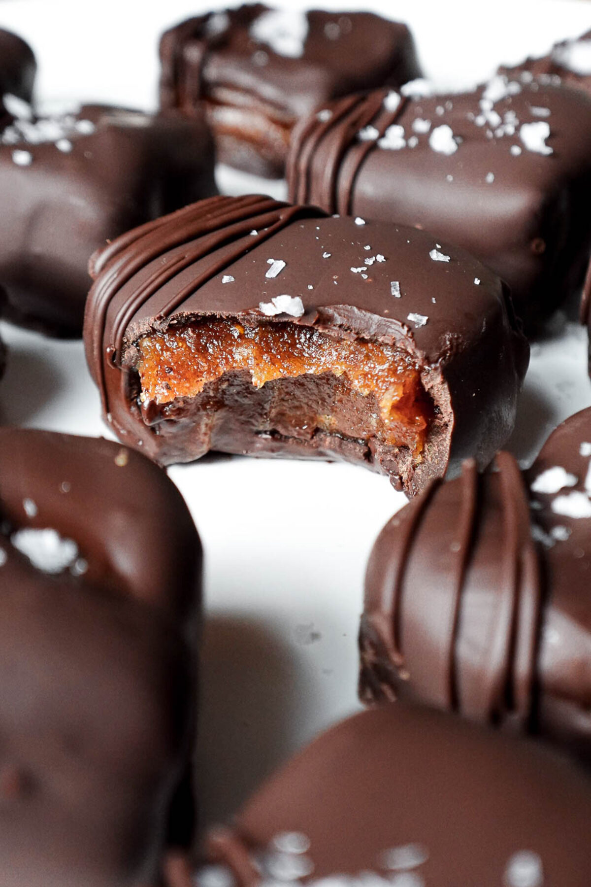 Close-up of a chocolate date caramel with a bite taken out showing it's gooey texture inside