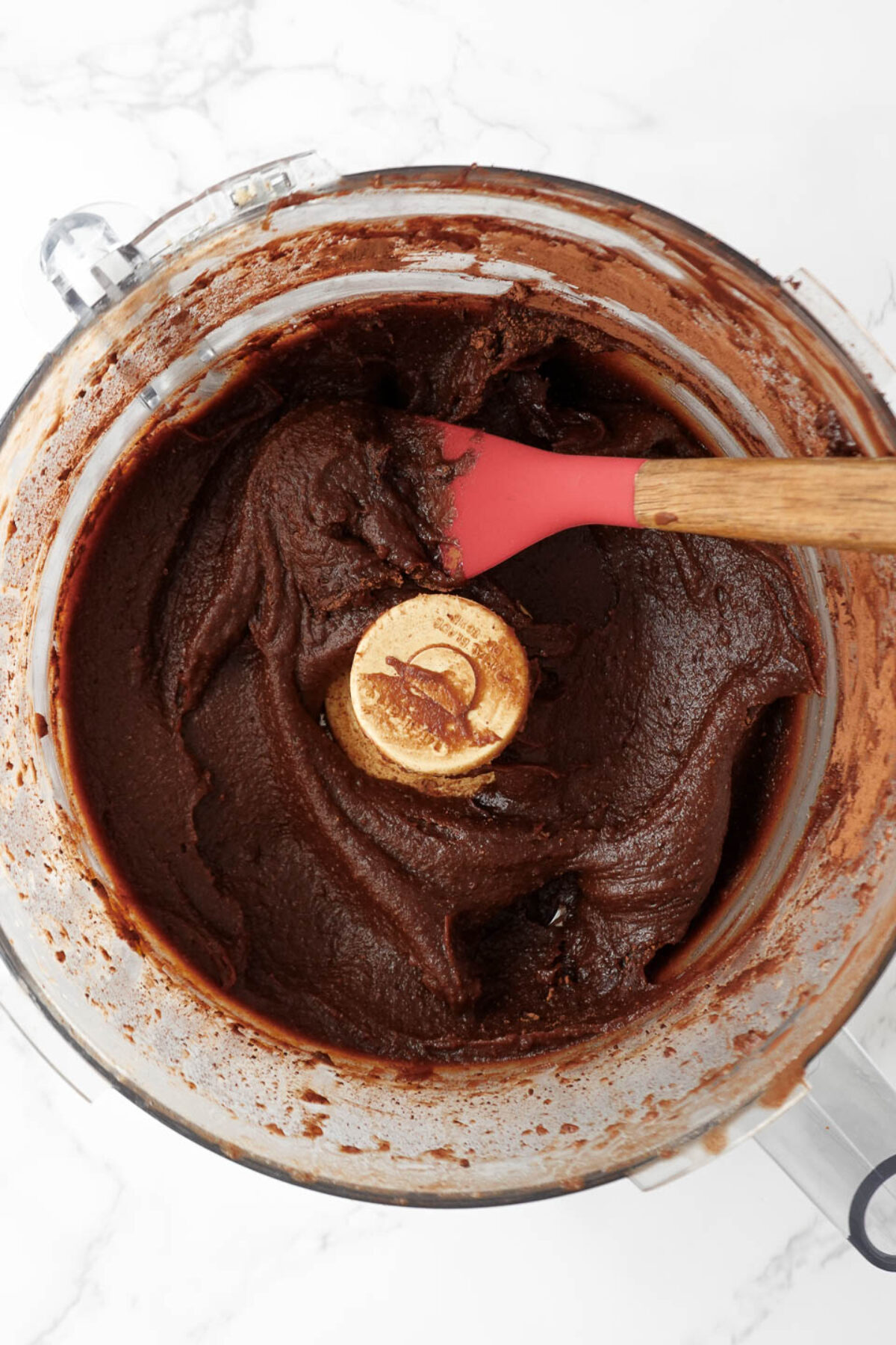 overhead shot of food processor blending hazelnuts and chocolate into a smooth and creamy chocolate spread.