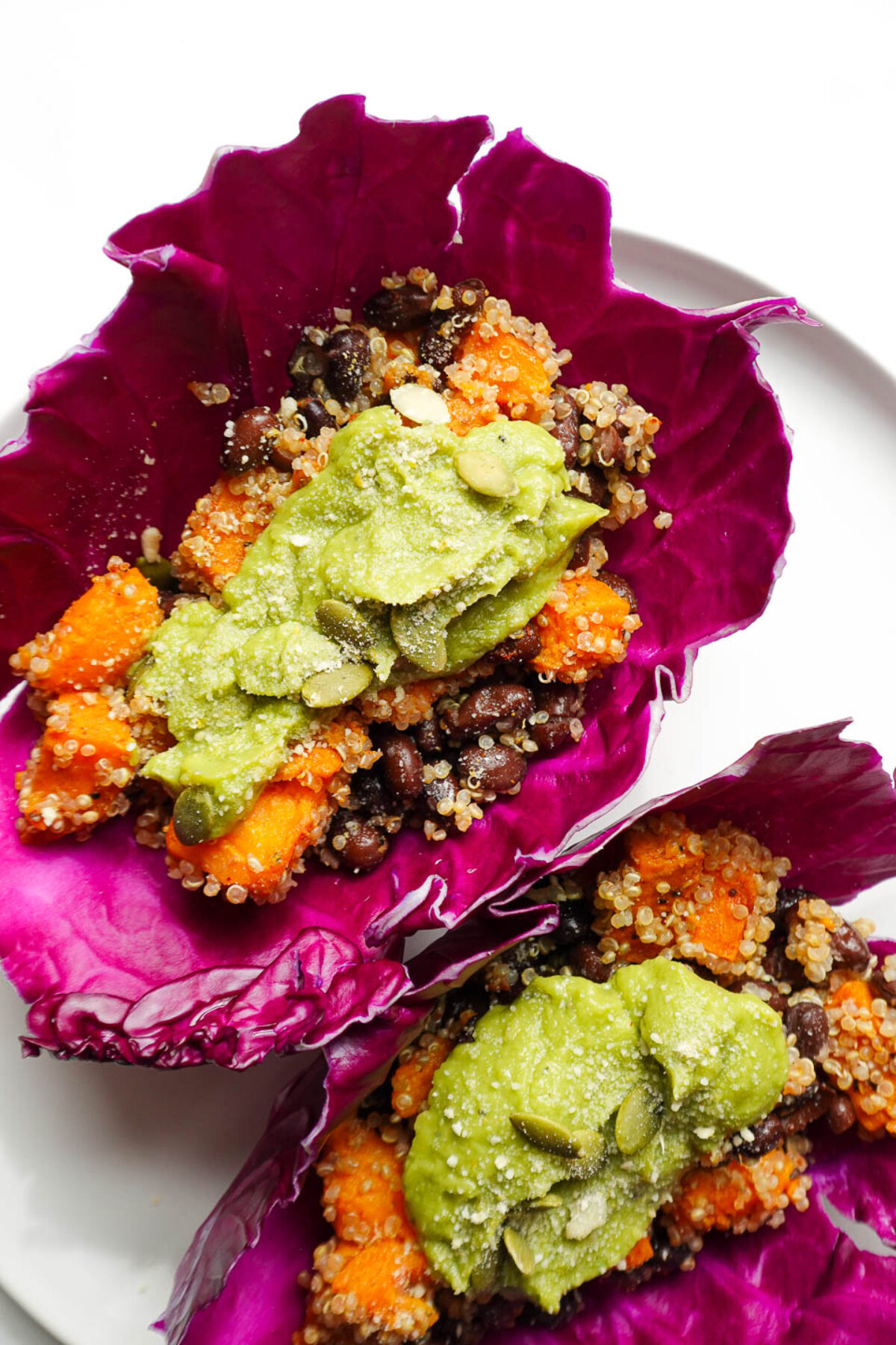 Close-up of vegan sweet potato and black beans tacos wrapped in red cabbage leaves.