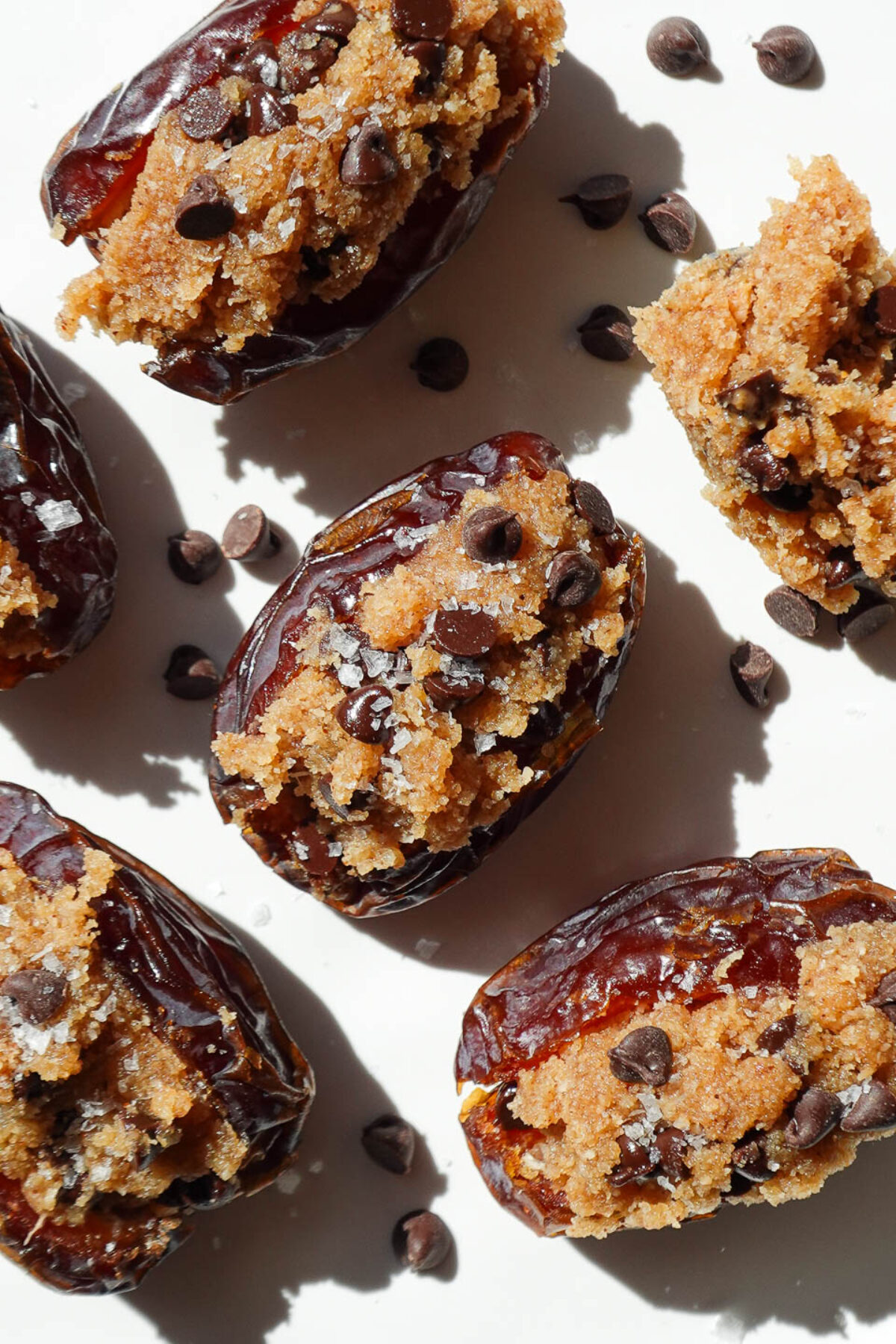 Close-up of cookie dough stuffed Medjool dates with chocolate chips and flaky sea salt on top.