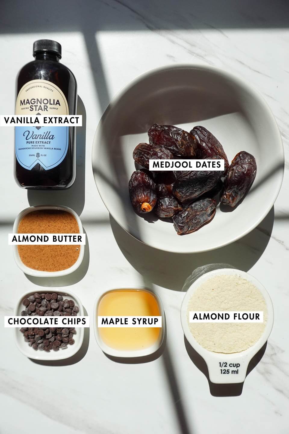 Ingredients for cookie dough stuffed dates including medjool dates, almond flour, almond butter, maple syrup, and chocolate chips