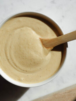 Smooth and creamy Lemon Tahini Dressing in a bowl with a wooden spoon