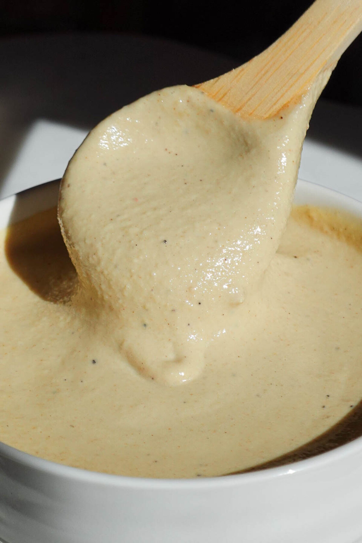 Spoon drizzling creamy lemon tahini dressing.