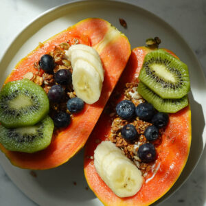 Finished papaya yogurt bowl topped with fresh fruit and granola ready to serve.