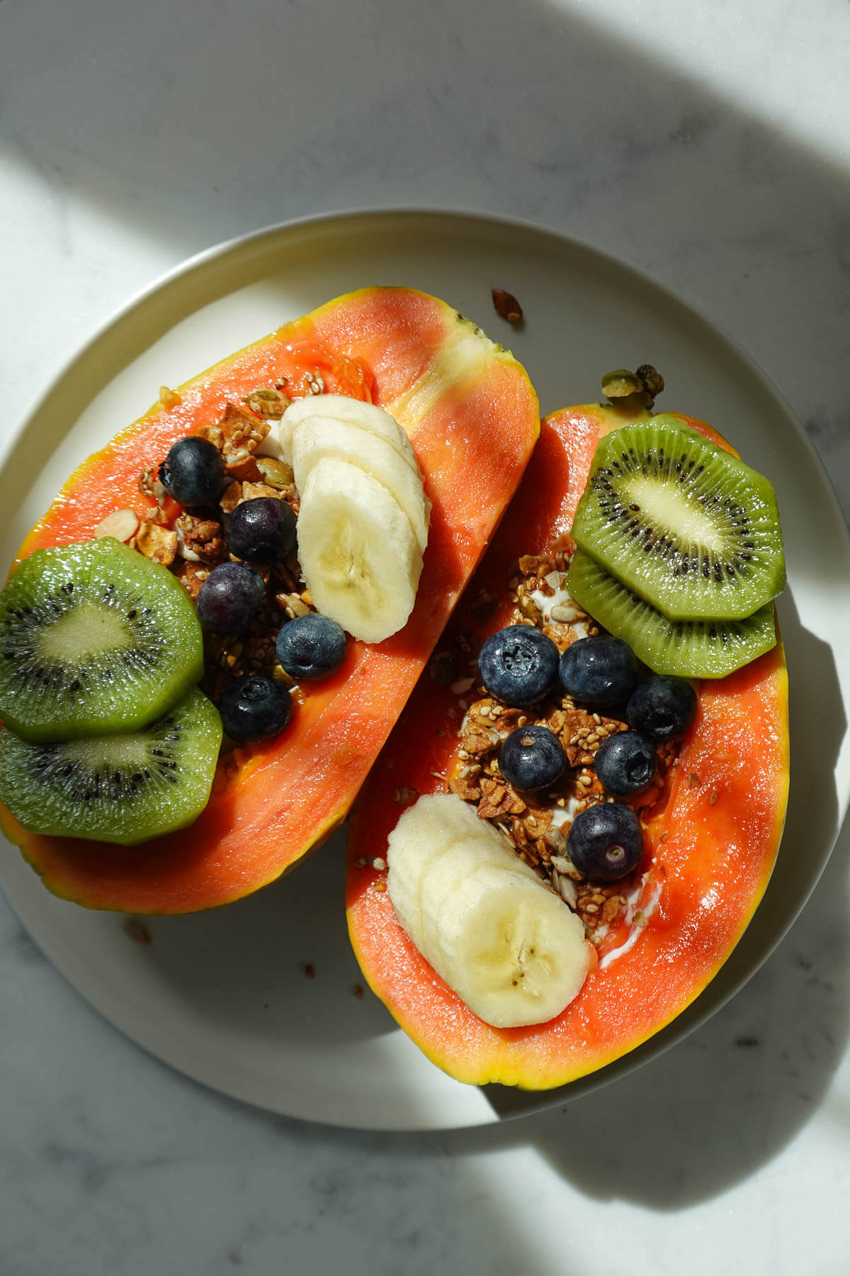 Finished papaya yogurt bowl topped with fresh fruit and granola ready to serve.