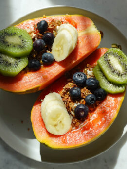 Papaya yogurt bowl topped with kiwis, blueberries, banana, and granola.