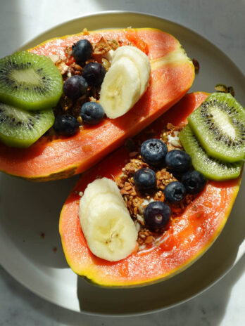 Papaya yogurt bowl topped with kiwis, blueberries, banana, and granola.