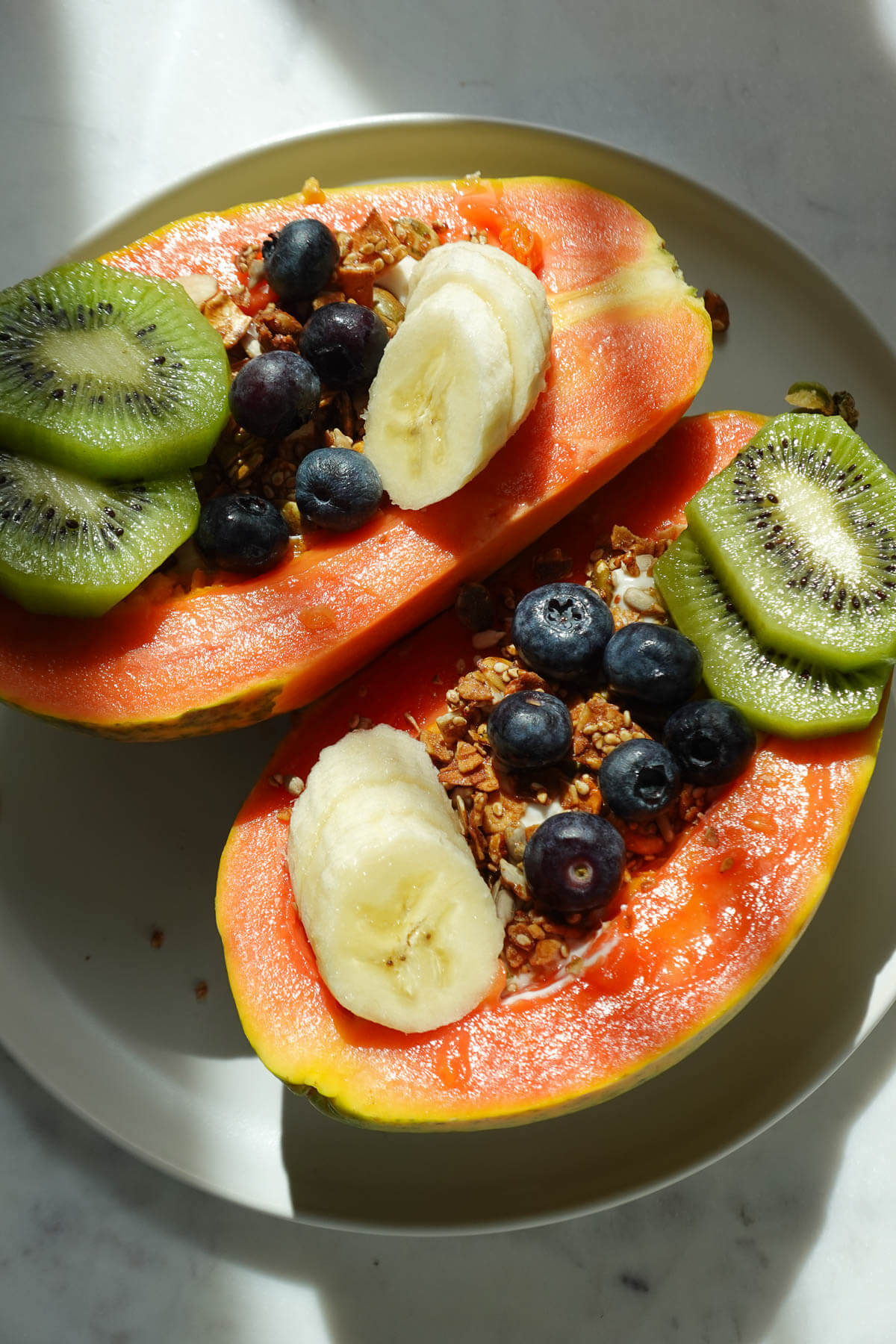 Papaya yogurt bowl topped with kiwis, blueberries, banana, and granola.
