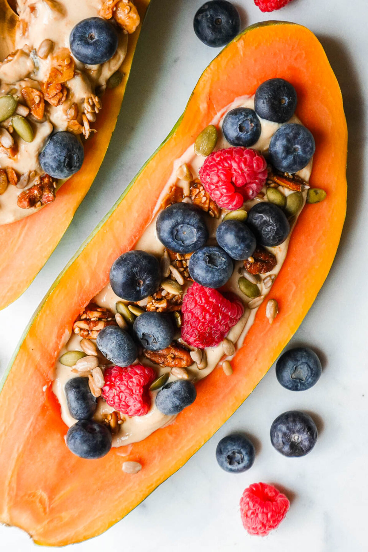 overhead shot of papaya breakfast bowl filled with yogurt, topped with fresh fruit, and granola.
