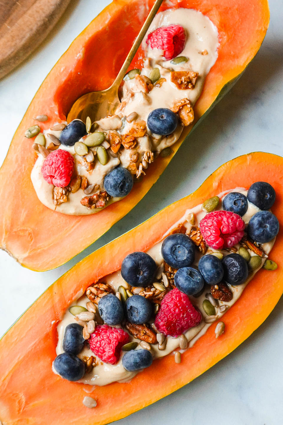 healthy papaya breakfast bowl filled with yogurt, topped with fresh fruit, and granola.