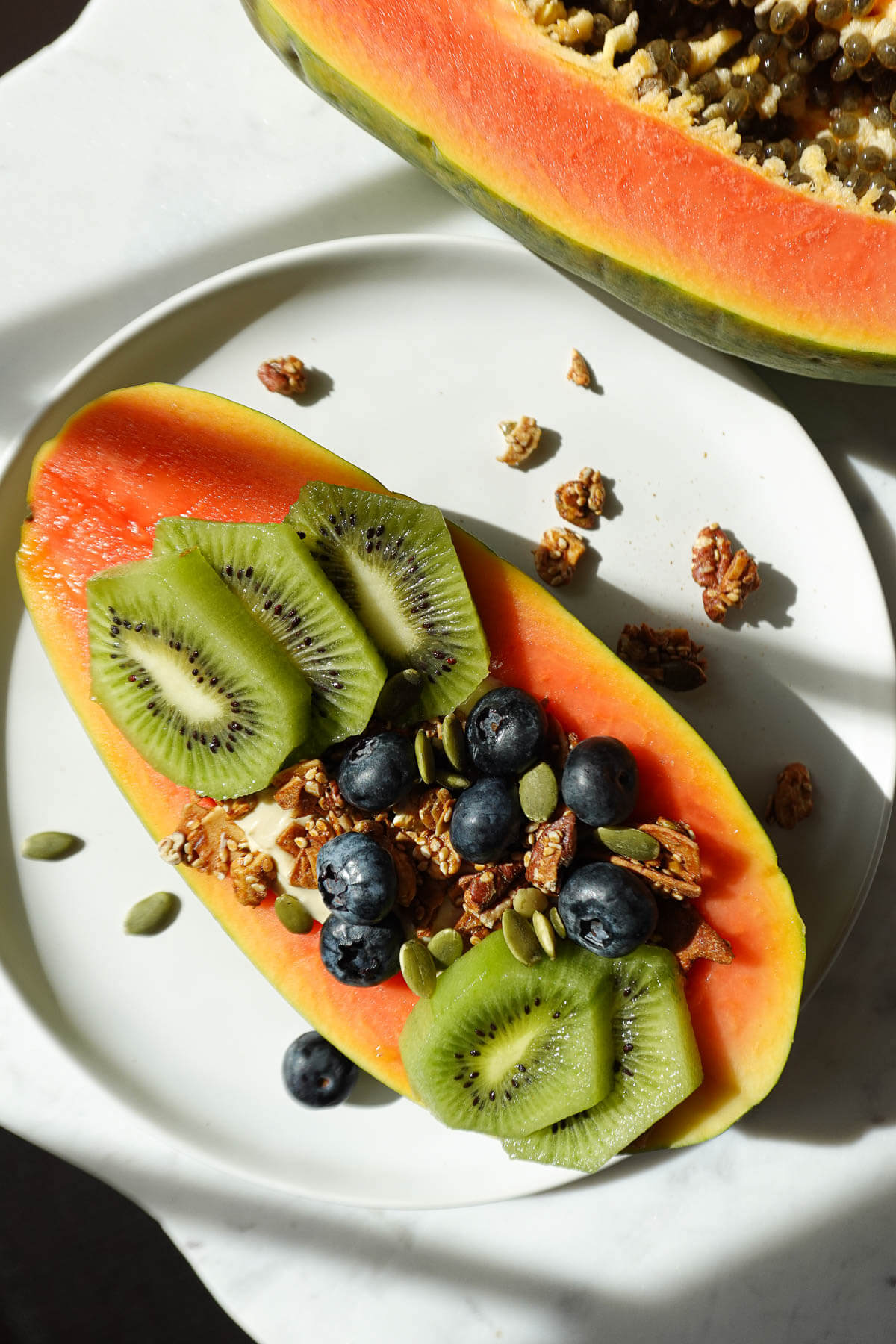 Papaya yogurt bowl topped with kiwis, blueberries, and granola.