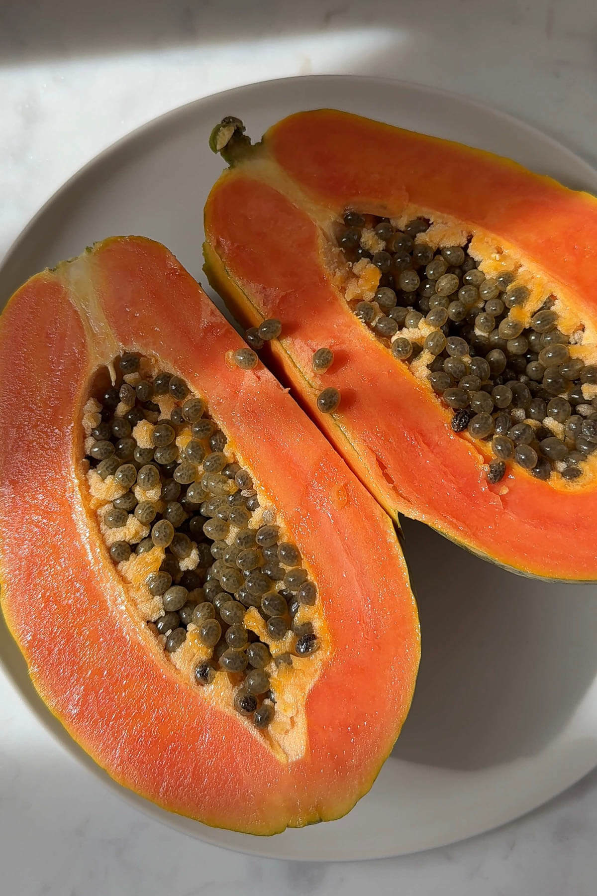 Cutting a ripe papaya in half and removing the seeds