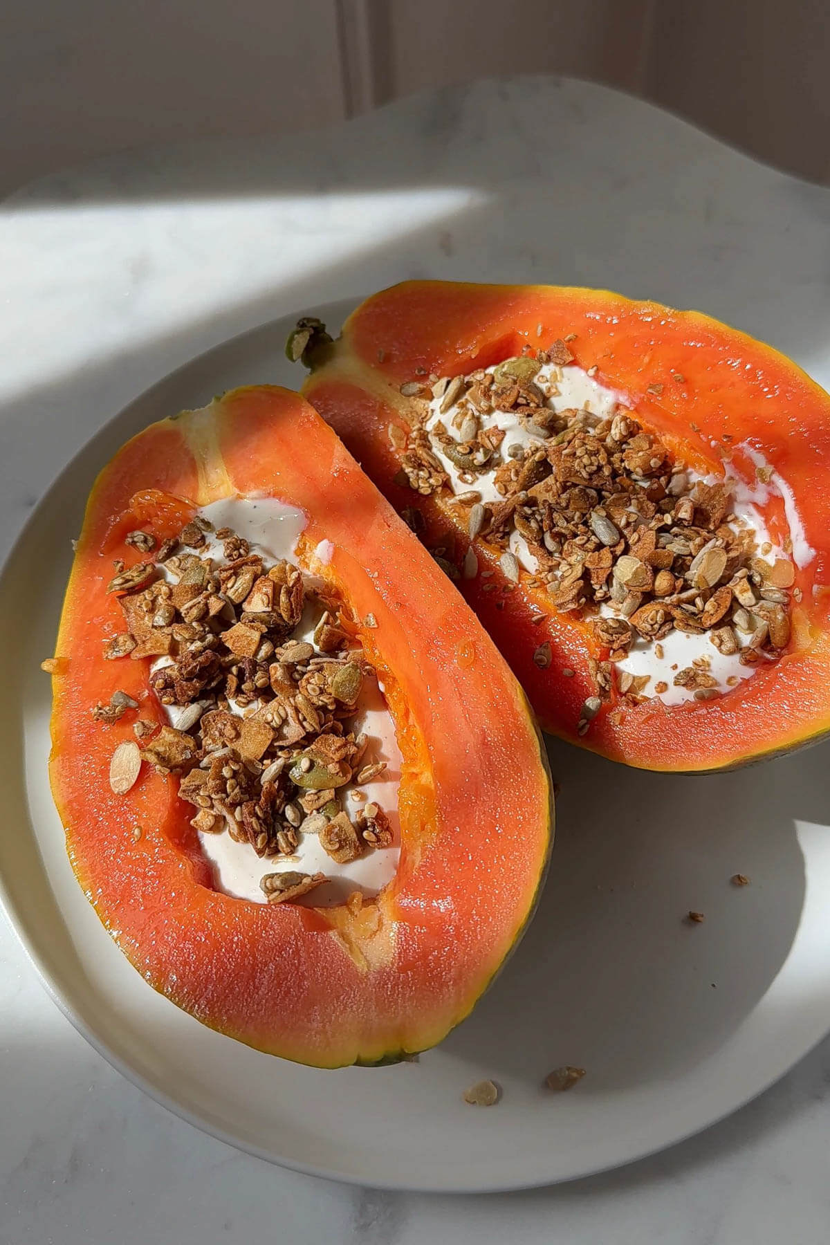 Filling papaya halves with vegan yogurt and granola.