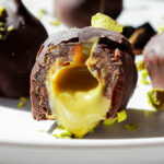 Pistachio stuffed date cut in half, showing creamy pistachio butter drizzling out, with a sprinkle of chopped pistachios on top.