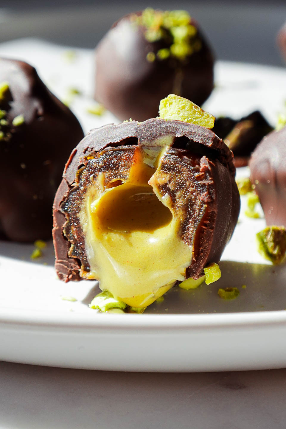 Pistachio stuffed date cut in half, showing creamy pistachio butter drizzling out, with a sprinkle of chopped pistachios on top.