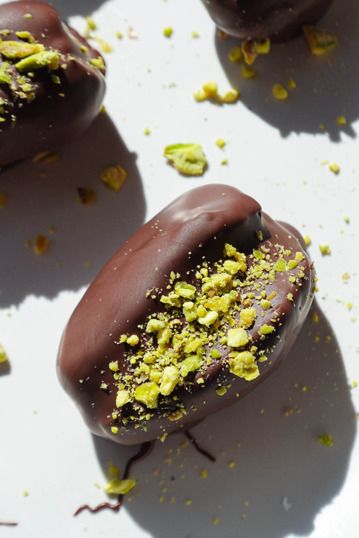 Close-up of pistachio stuffed dates covered in chocolate and topped with chopped pistachios.