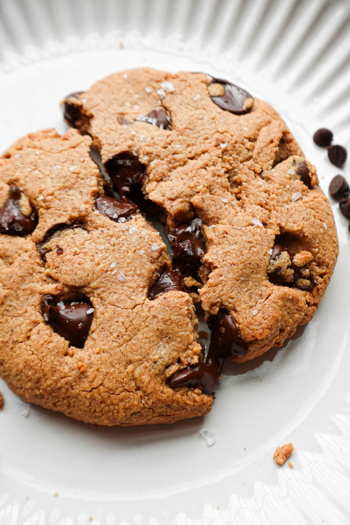 Close-up of a soft and chewy chocolate chip cookie split in two, with melted chocolate stretching between the halves.