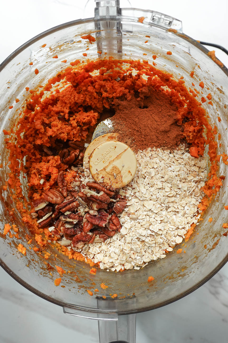adding dry ingredients to food processor to make carrot cake energy balls
