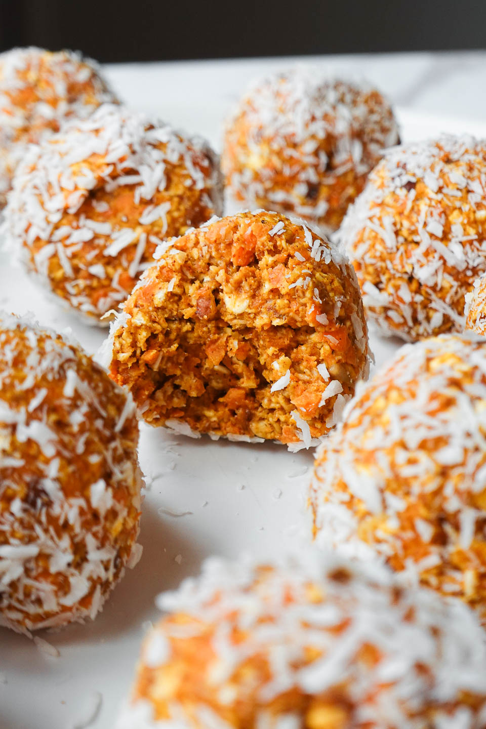 Soft carrot cake energy ball with. bite taken out showing chewy, soft texture inside