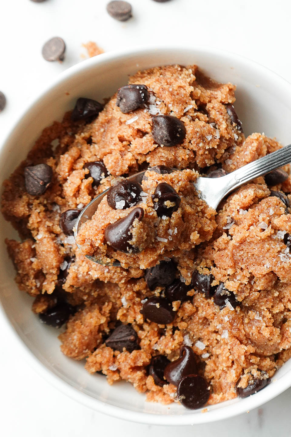 A spoonful of healthy edible cookie dough with maple syrup, almond butter, and chocolate chips.