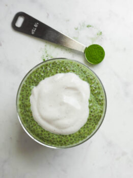 Overhead shot of matcha chia pudding in a glass jar topped with yogurt