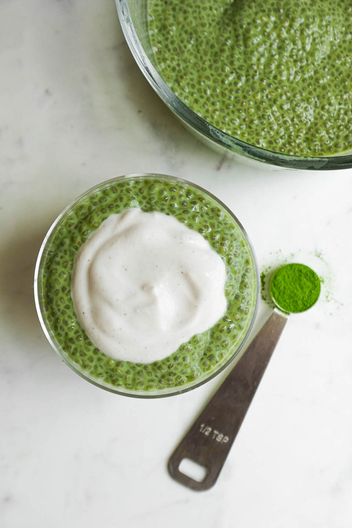 Overhead shot of matcha chia pudding in a glass jar topped with yogurt
