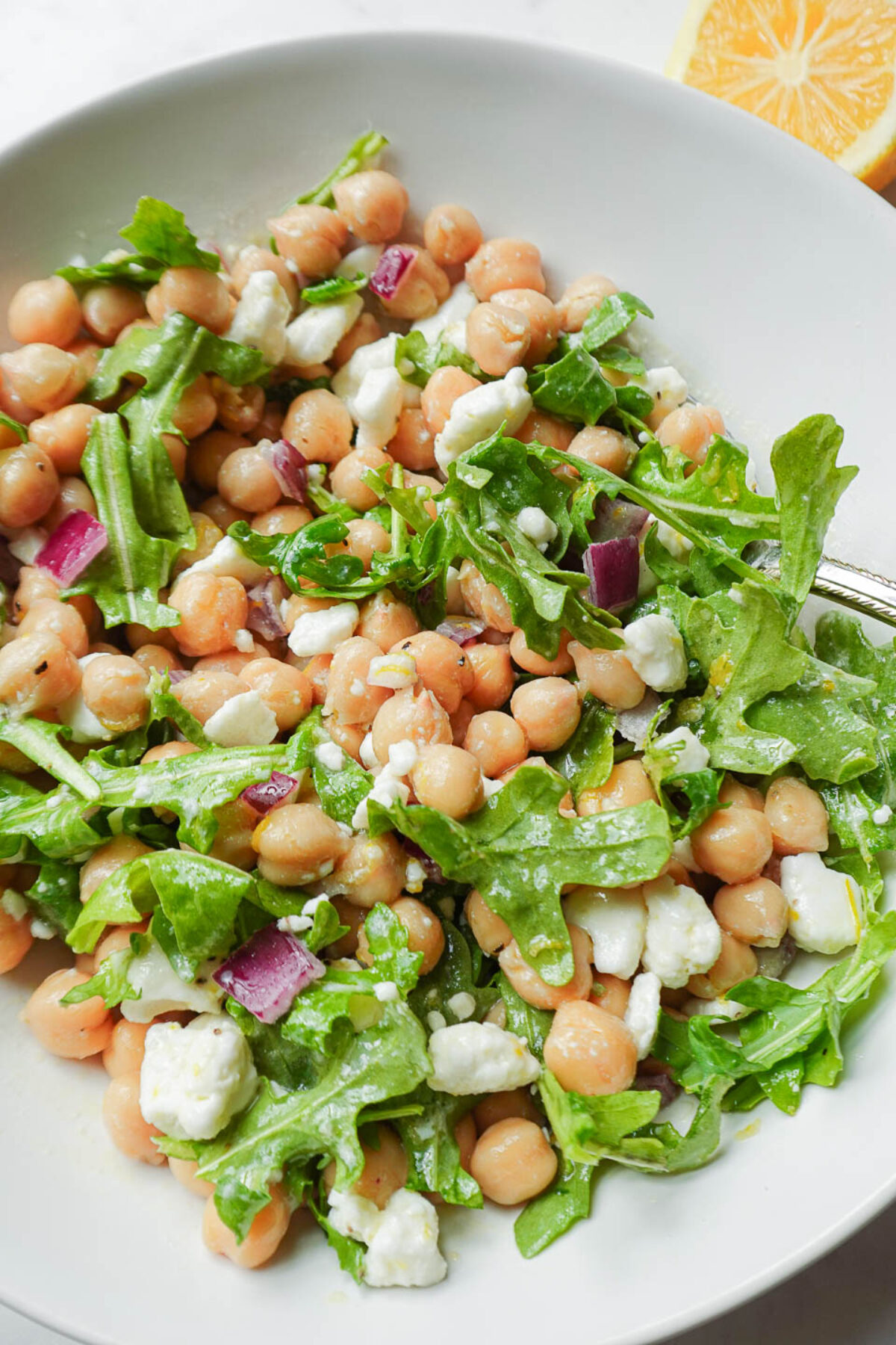 Close-up spoonful of vegan chickpea salad with feta, arugula, and chickpeas coated in lemon vinaigrette