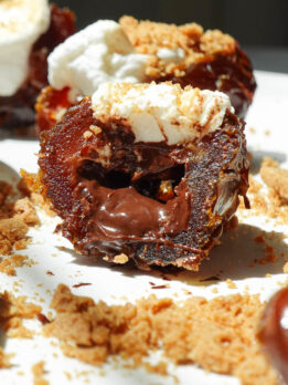 Gooey vegan S’mores Stuffed Date filled with melted dark chocolate and toasted vegan marshmallow and topped with crushed graham crackers