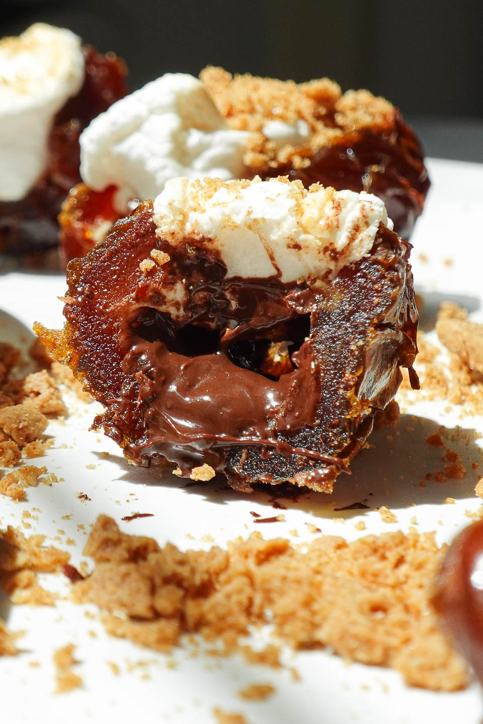 Gooey vegan S’mores Stuffed Date filled with melted dark chocolate and toasted vegan marshmallow and topped with crushed graham crackers