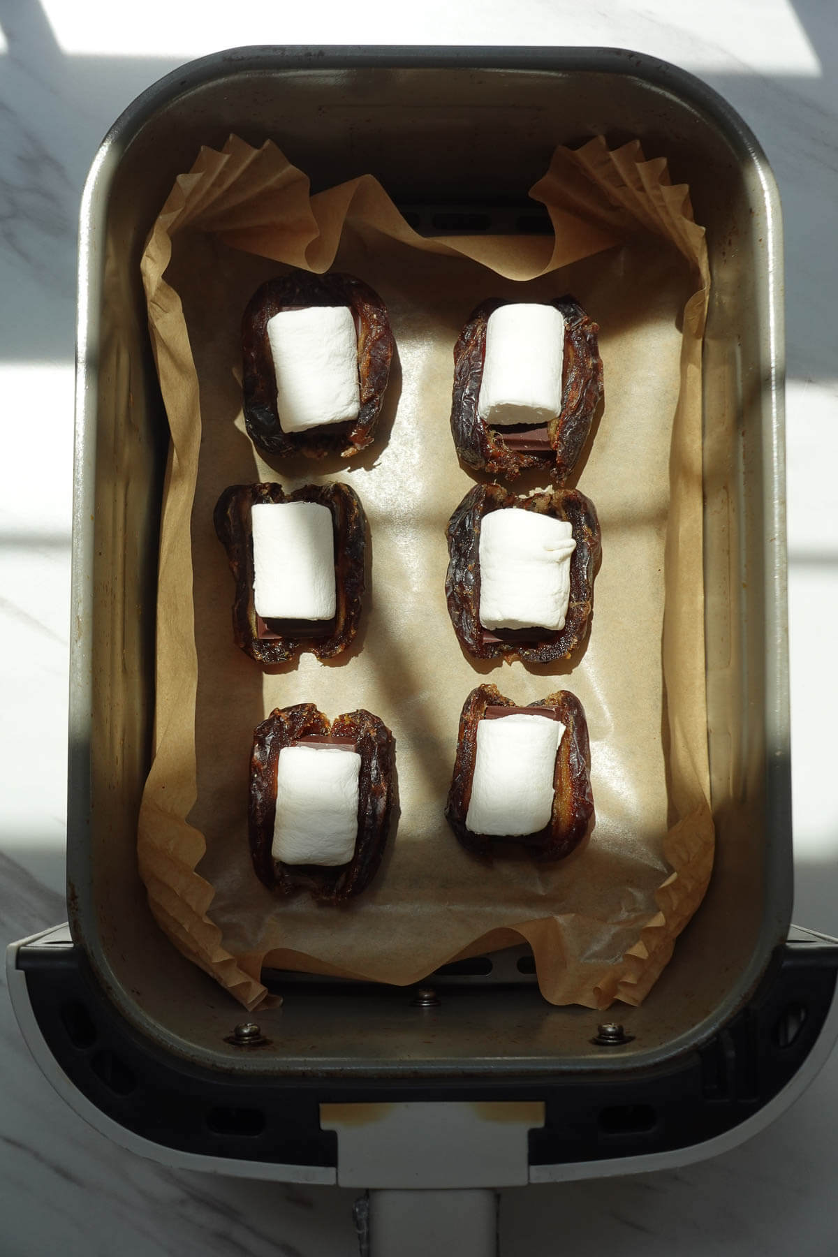 S'mores stuffed dates in an air fryer basket.
