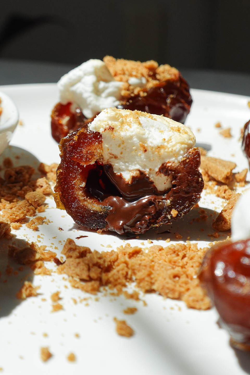 Close-up bite of a S’mores Stuffed Date showing melty chocolate and toasted marshmallow center