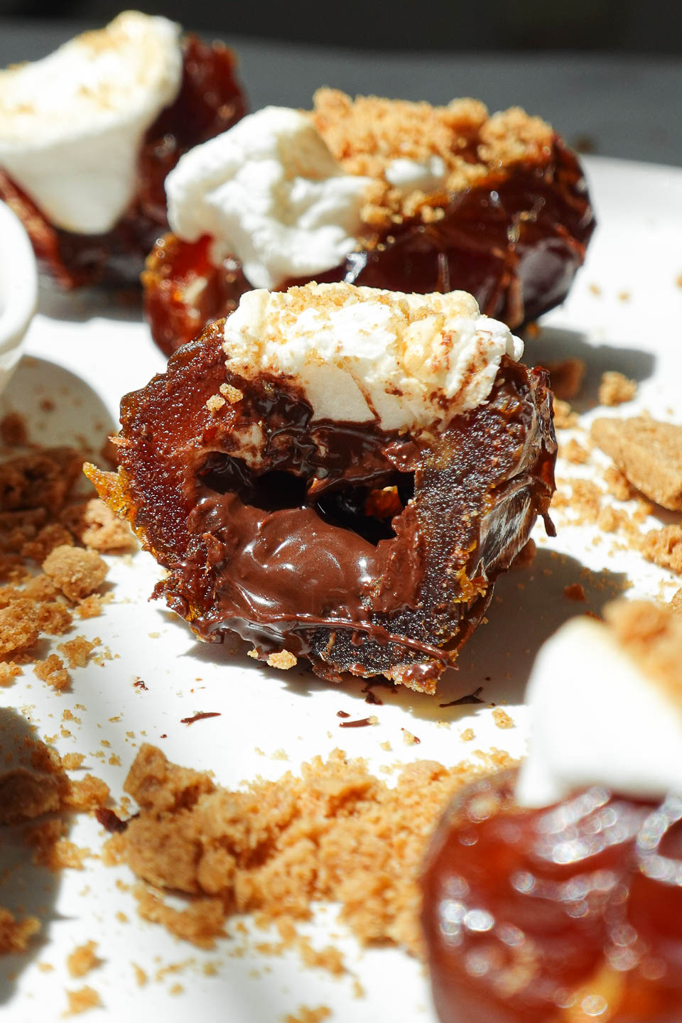 Close-up bite of a S’mores Stuffed Date showing melty chocolate and toasted marshmallow center