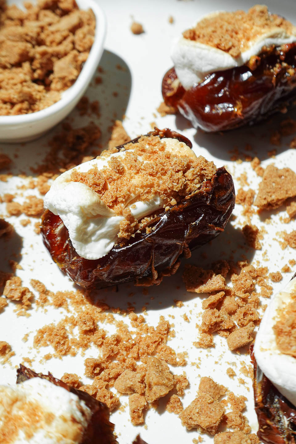 Vegan S’mores Stuffed Dates on a white plate topped with crushed graham crackers