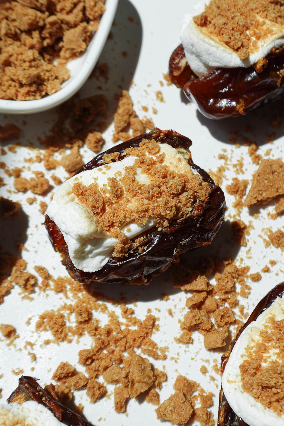 Vegan S’mores Stuffed Dates on a white plate topped with crushed graham crackers