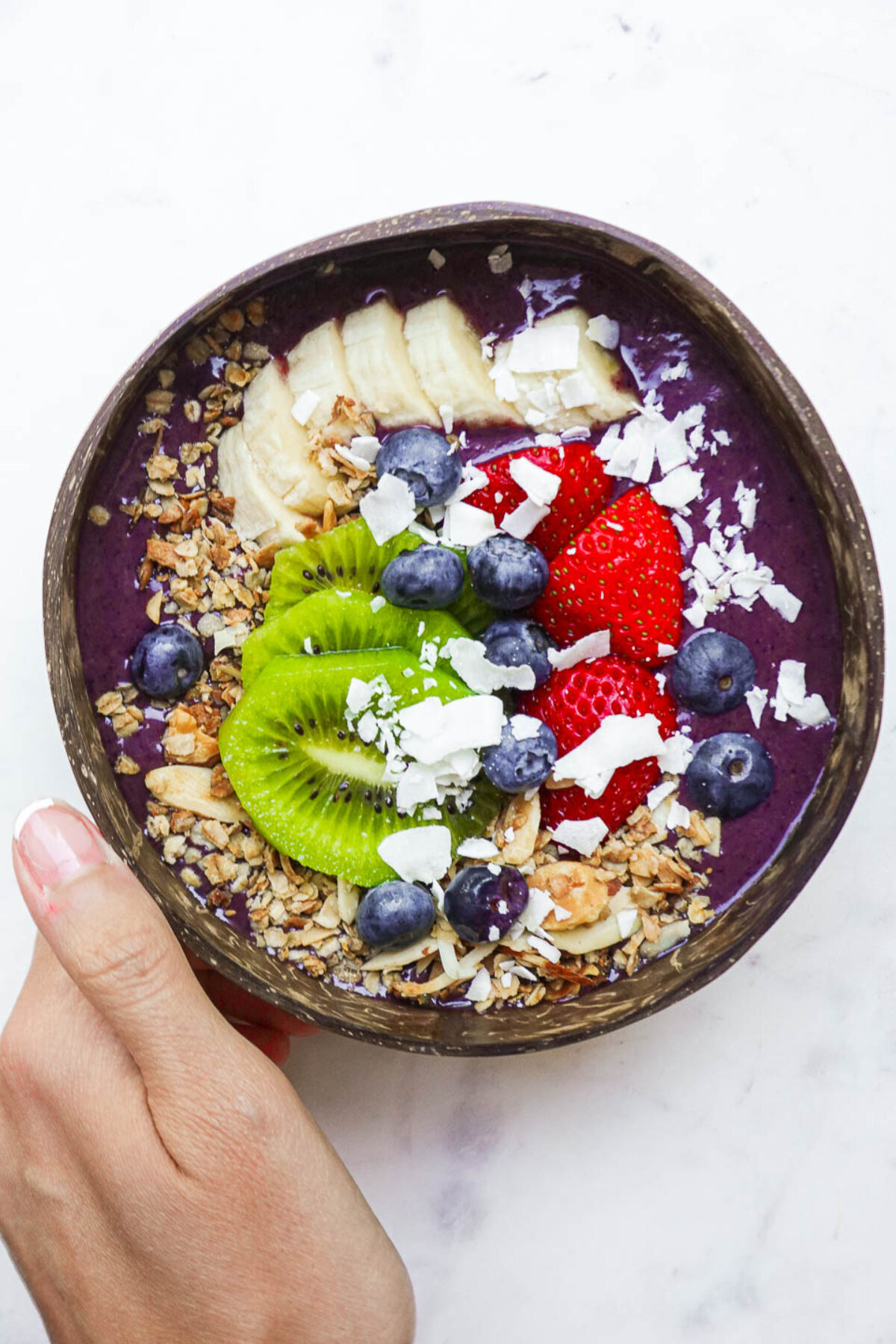 Homemade acai bowl served in a coconut bowl with fresh fruit and toppings