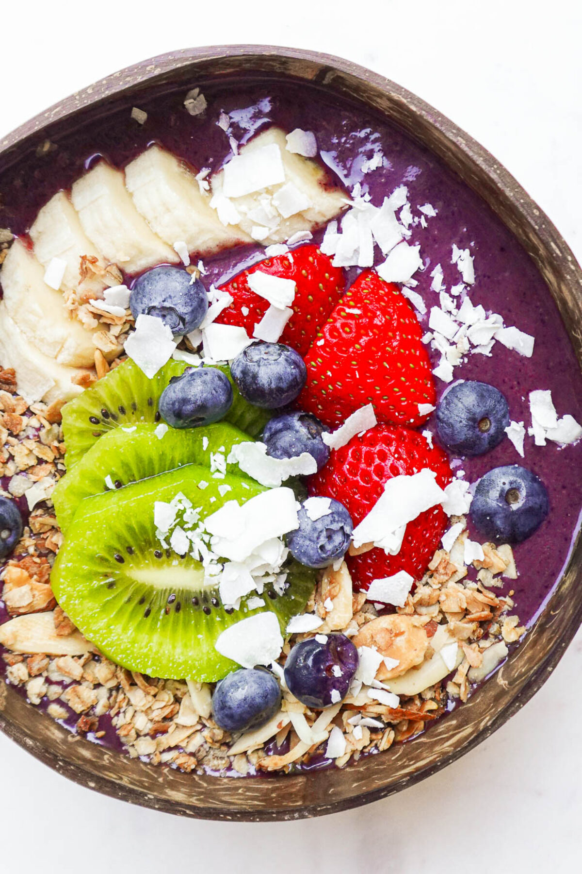 Thick and creamy berry acai bowl with granola, fresh fruit, and sliced banana