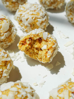 Close-up of a mango bliss ball with a chewy, coconut-covered texture.
