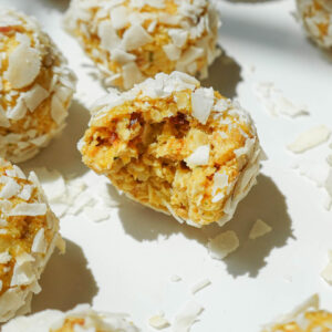 Close-up of a mango bliss ball with a chewy, coconut-covered texture.