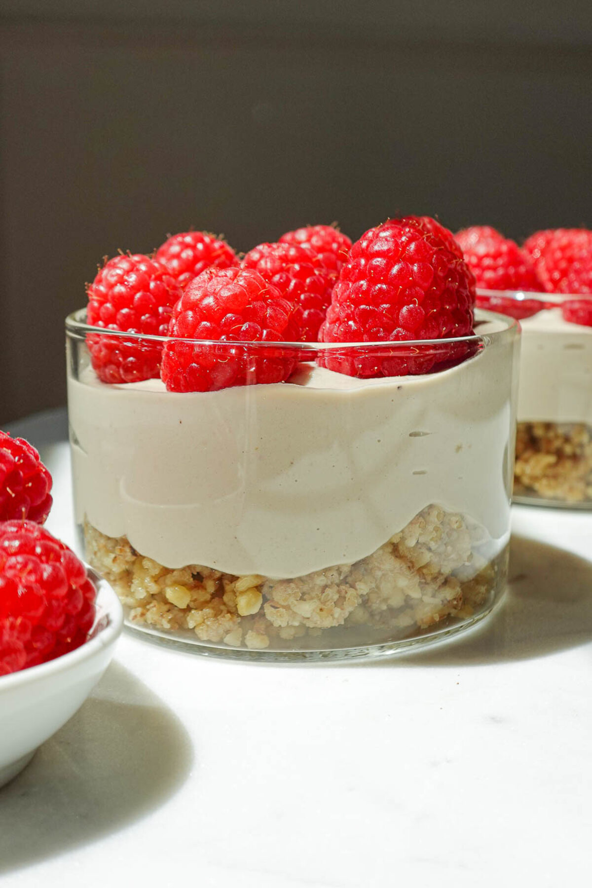 individual vegan raspberry cheesecake jars in clear glass jars, perfect for summer dessert or parties