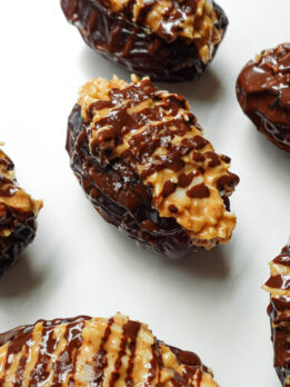 Close-up of Samoas Stuffed Dates drizzled with melted chocolate and sprinkled with coconut flakes