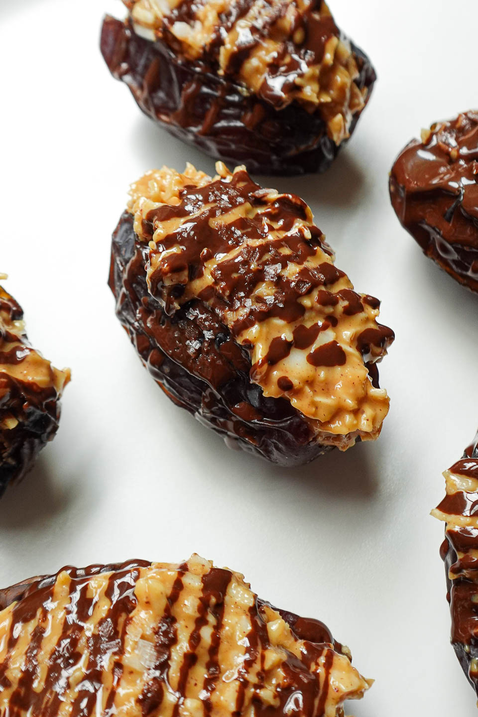 Close-up of Samoas Stuffed Dates drizzled with melted chocolate and sprinkled with coconut flakes