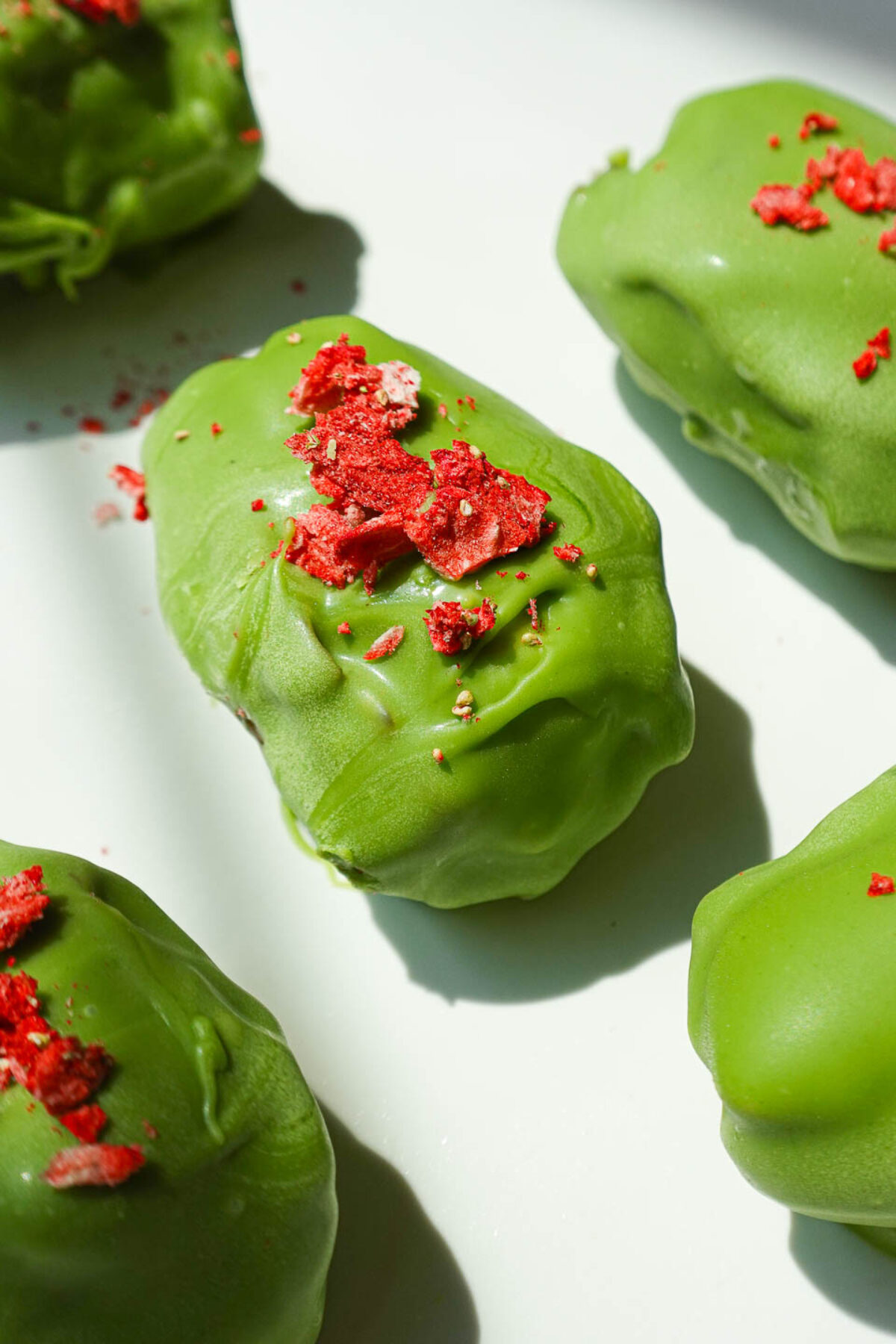 Strawberry matcha stuffed dates coated in vegan white chocolate and topped with crushed freeze-dried strawberries