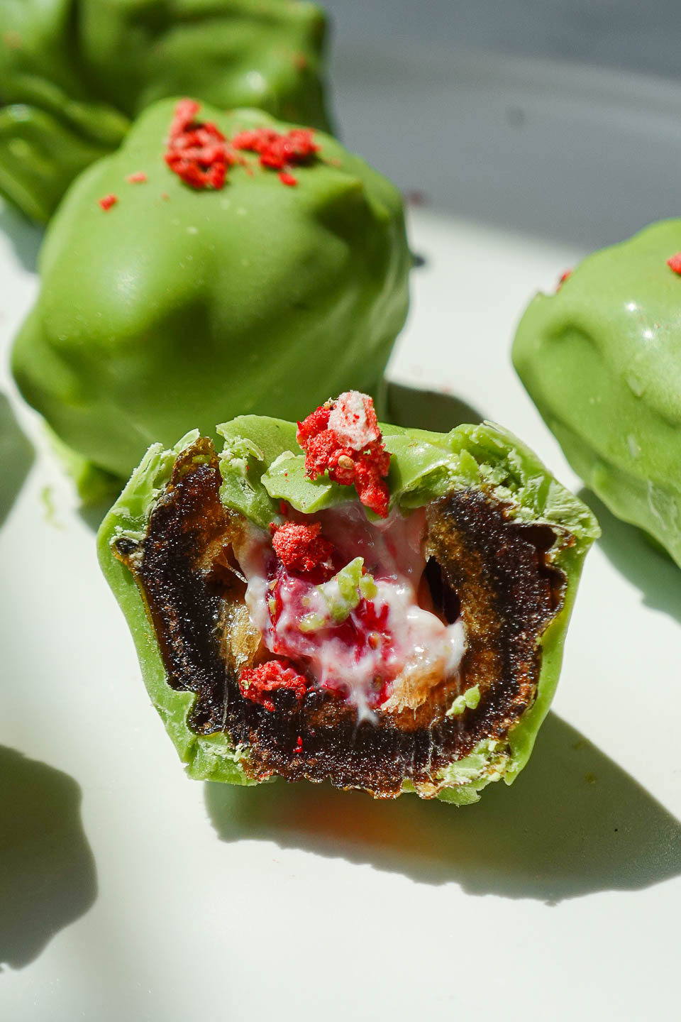 Inside view of a stuffed Medjool date filled with strawberry yogurt and coated in matcha white chocolate