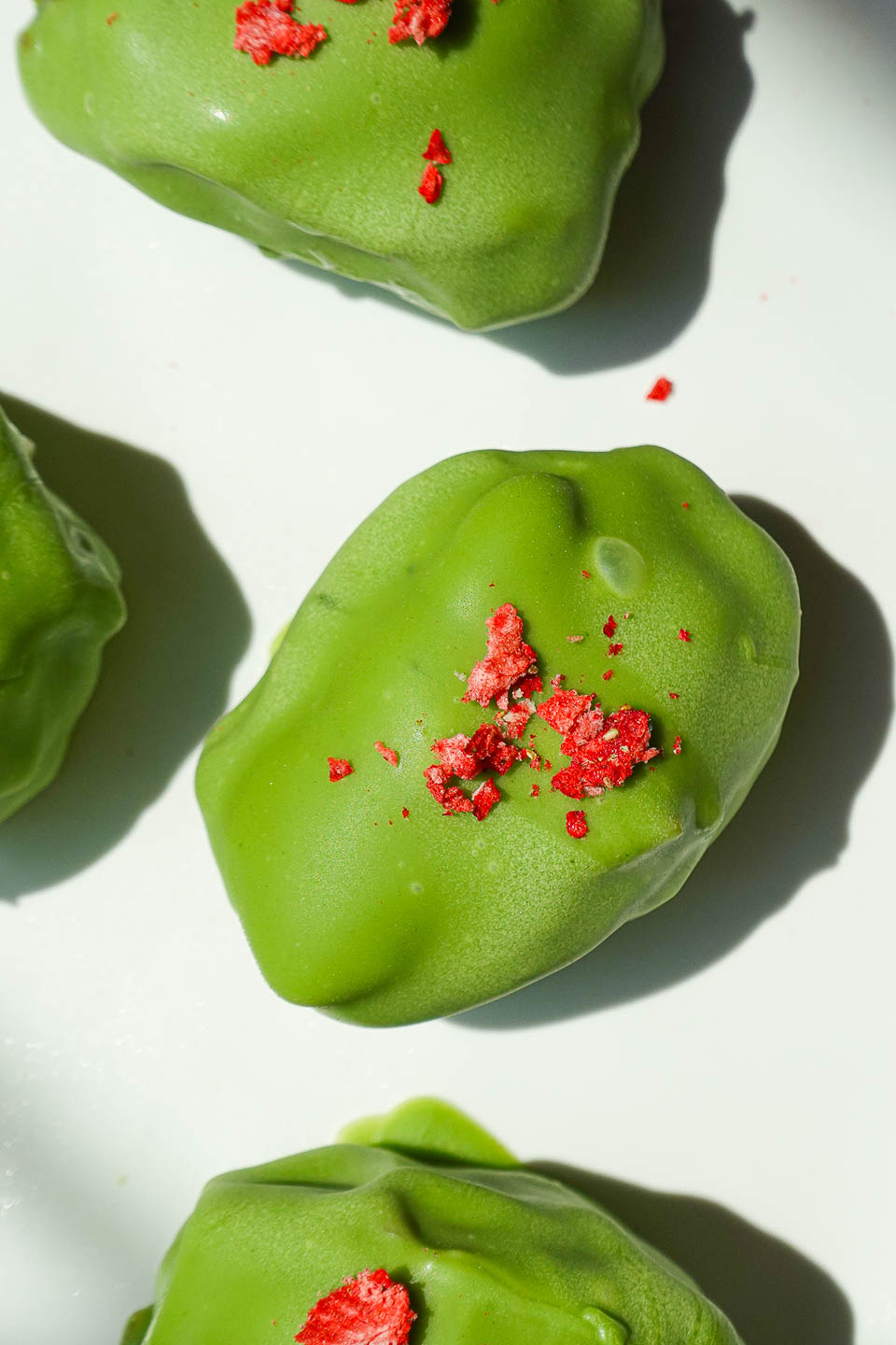 No-bake vegan strawberry matcha stuffed dates with matcha white chocolate shell and crushed freeze dried strawberries